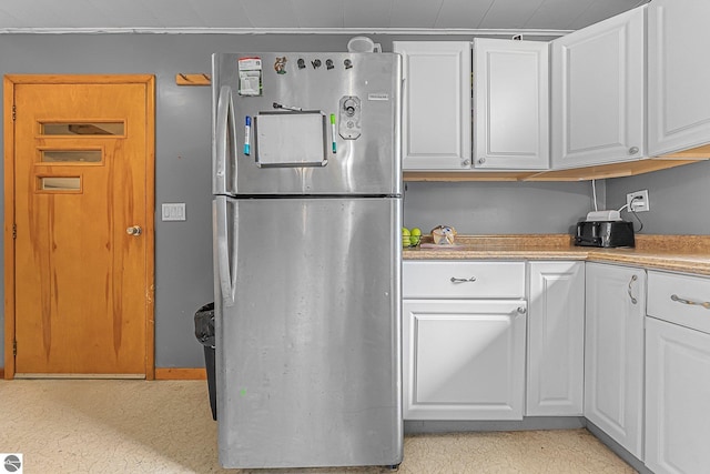 1981 S Lake Mitchell Dr, Cadillac, MI 49601 - kitchen with light floors, white cabinets, and freestanding refrigerator