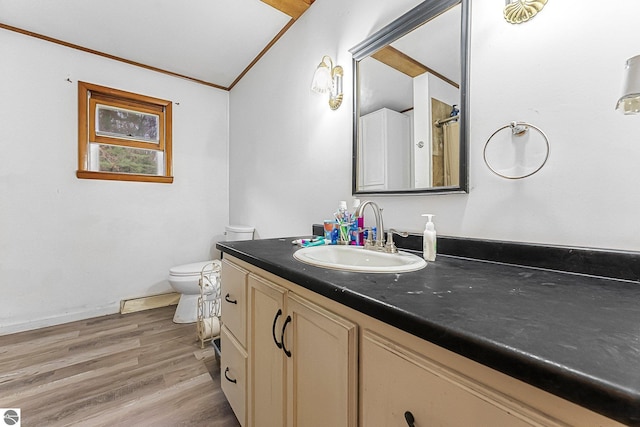 1981 S Lake Mitchell Dr, Cadillac, MI 49601 - bathroom with vaulted ceiling, wood finished floors, vanity, toilet, and ornamental molding