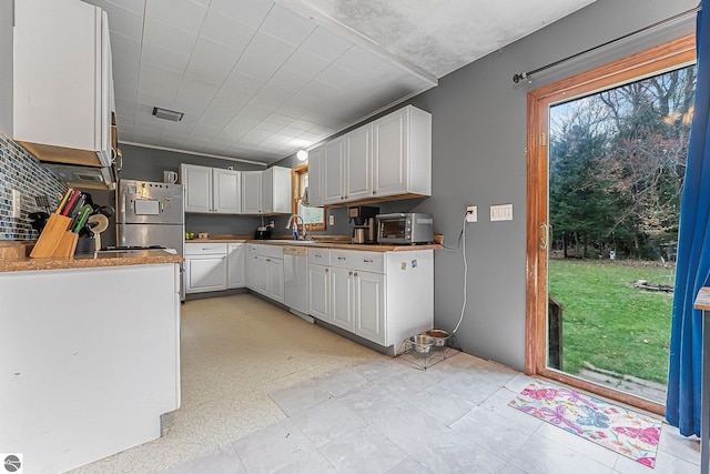 1981 S Lake Mitchell Dr, Cadillac, MI 49601 - kitchen with white dishwasher, plenty of natural light, a sink, and a toaster