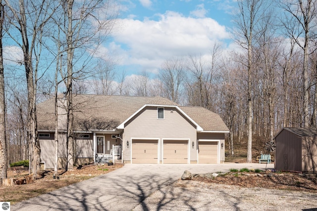 view of front of property featuring a garage, roof with shingles, a shed, an outbuilding, and driveway