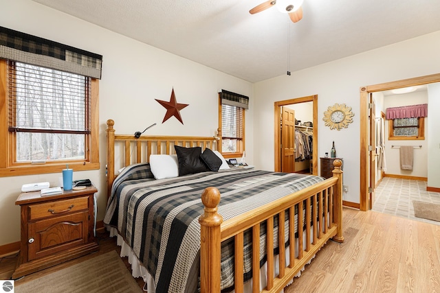 bedroom with multiple windows, a closet, light wood-type flooring, and a spacious closet