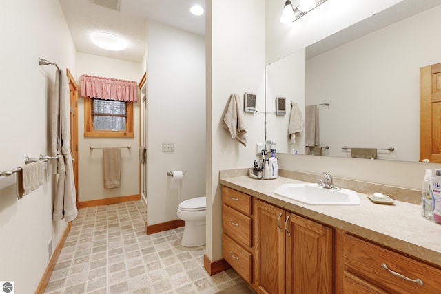 bathroom with vanity, baseboards, a shower with door, and toilet