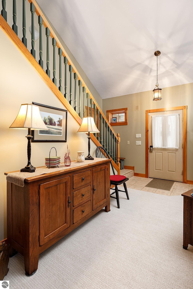 entryway featuring baseboards, light carpet, and stairway
