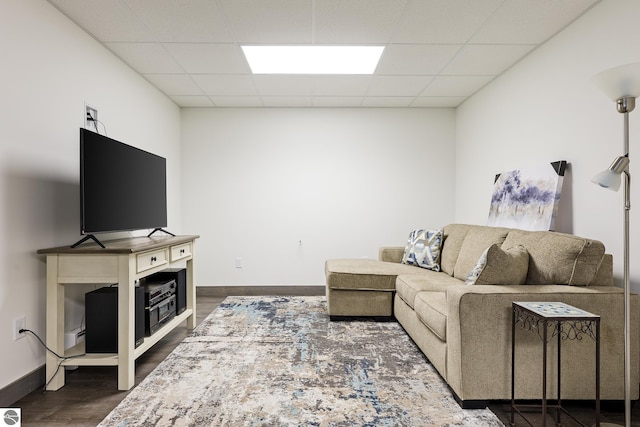 living room featuring baseboards, dark wood finished floors, and a drop ceiling