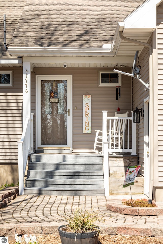 entrance to property featuring a shingled roof and a porch