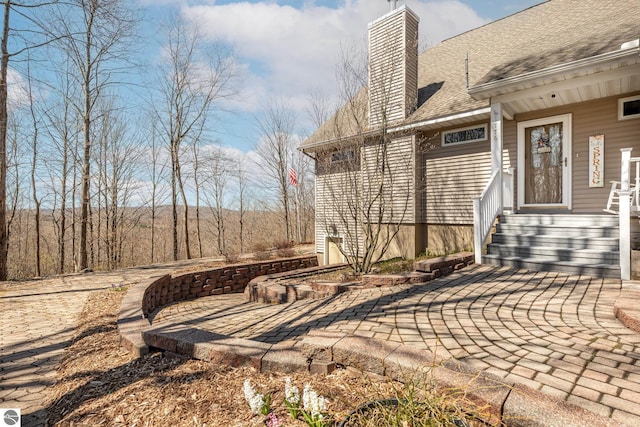 exterior space with a chimney and roof with shingles