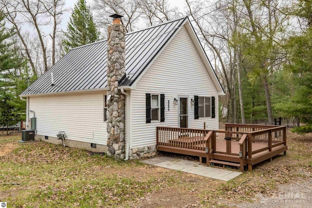 rear view of property featuring a chimney, a standing seam roof, metal roof, central air condition unit, and a deck