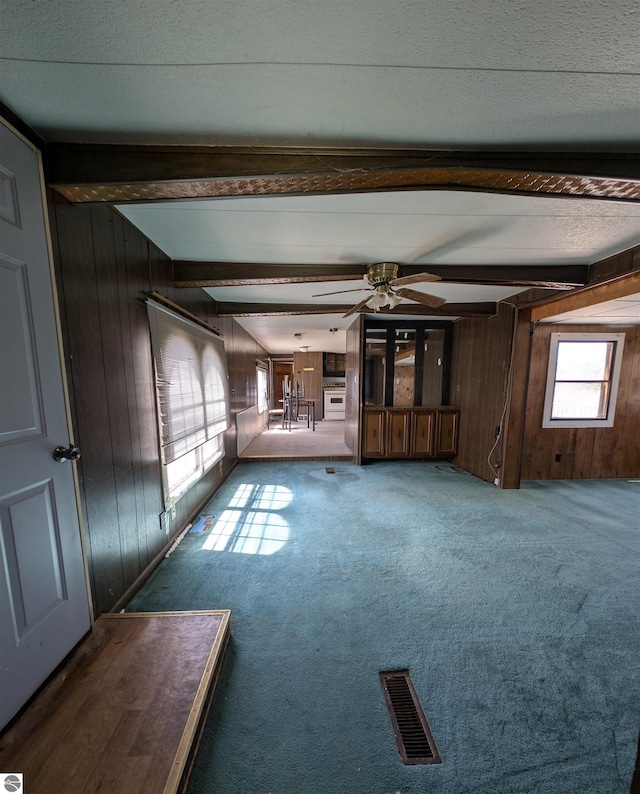interior space with beamed ceiling, wooden walls, and visible vents