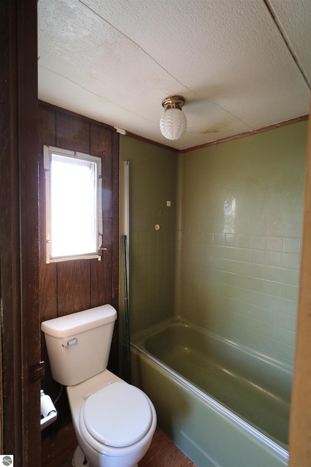 full bathroom with a textured ceiling, toilet, and wood finished floors