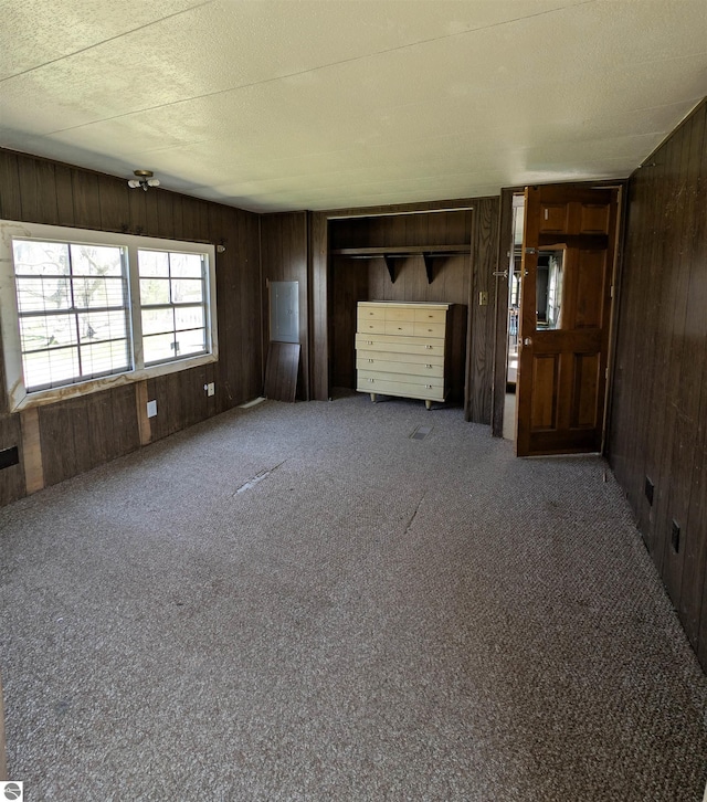 unfurnished living room with wood walls and carpet flooring