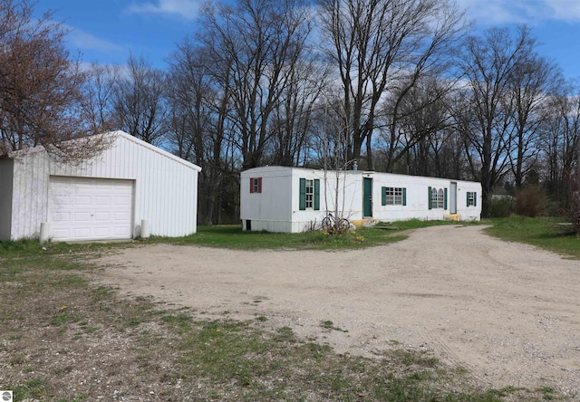view of front facade with dirt driveway, an outdoor structure, and a garage