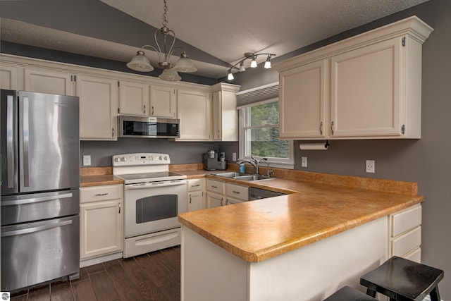 4215 Hearthside Dr, Traverse City, MI 49684 - kitchen with a peninsula, a sink, a textured ceiling, appliances with stainless steel finishes, and dark wood-style floors
