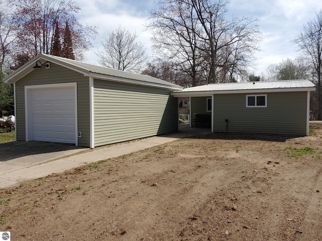 view of front of house featuring an outdoor structure, driveway, metal roof, and a detached garage