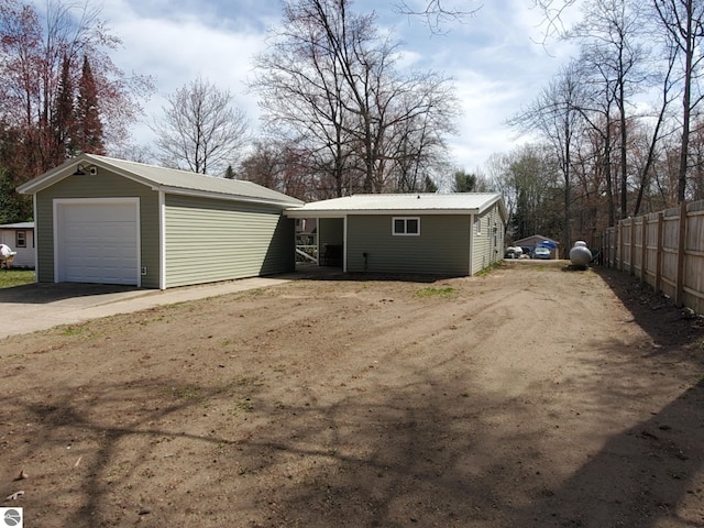 view of front of home with driveway, fence, metal roof, an outdoor structure, and a garage