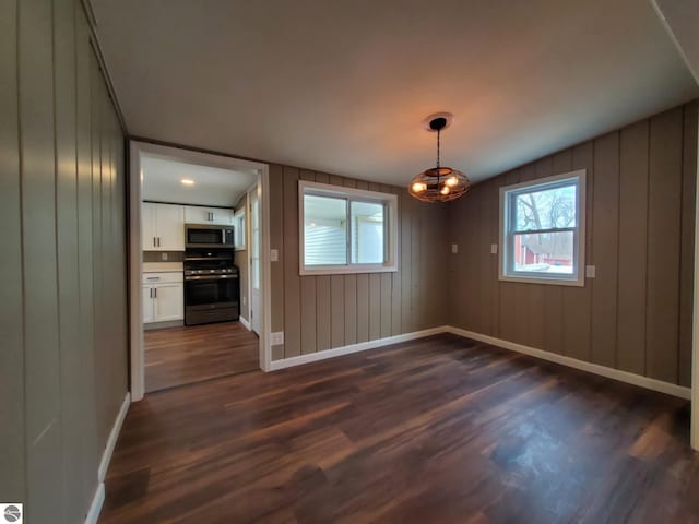 unfurnished dining area with baseboards, dark wood finished floors, and an inviting chandelier