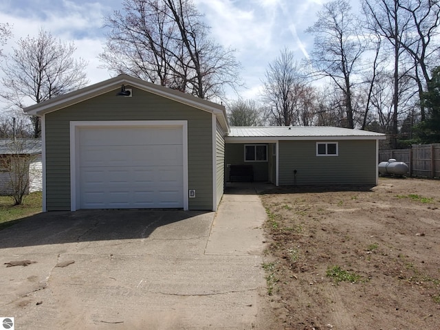 ranch-style home with a garage, fence, metal roof, and aphalt driveway