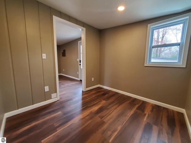 empty room with dark wood-type flooring, baseboards, and recessed lighting