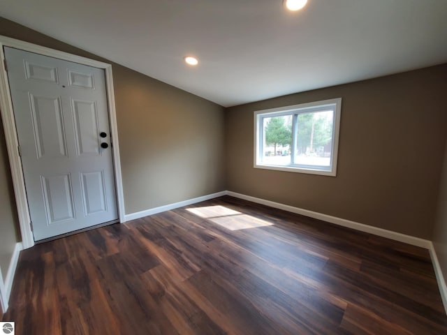 unfurnished room featuring dark wood-type flooring, baseboards, lofted ceiling, and recessed lighting