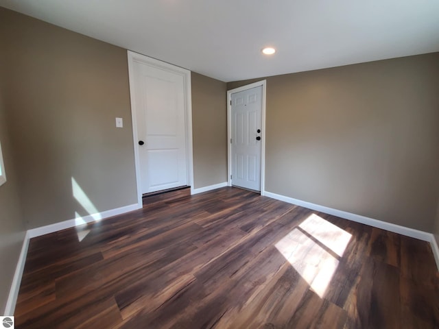 spare room featuring baseboards, recessed lighting, and dark wood-type flooring