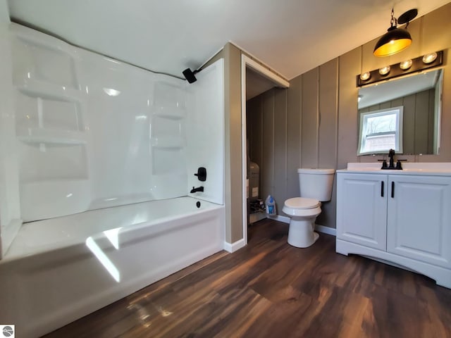 bathroom with toilet, tub / shower combination, wood finished floors, baseboards, and vanity