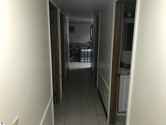 hall featuring light tile patterned flooring and baseboards