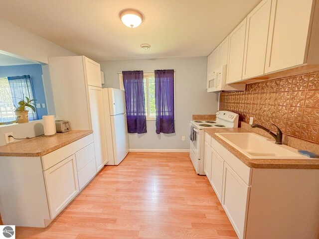 9166 Michigan Ave, Saint Helen, MI 48656 - kitchen featuring white appliances, a sink, white cabinetry, tasteful backsplash, and light wood-type flooring