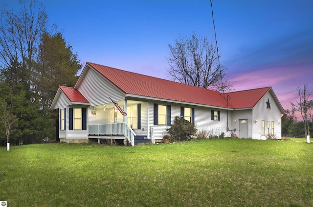 ranch-style home with covered porch, a yard, and metal roof
