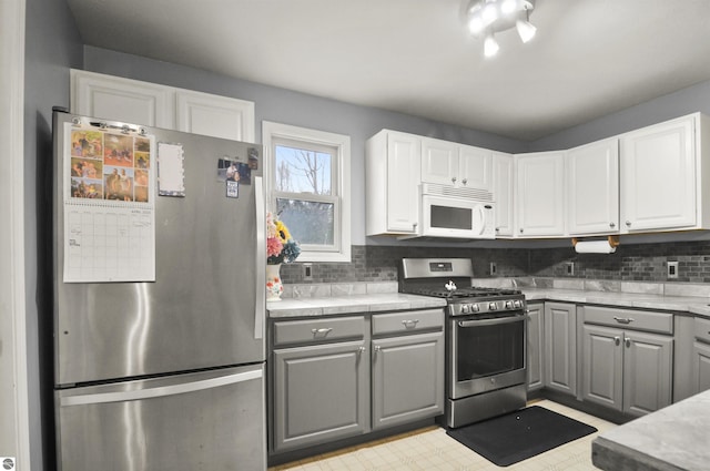 kitchen with stainless steel appliances, tasteful backsplash, white cabinetry, light countertops, and gray cabinetry