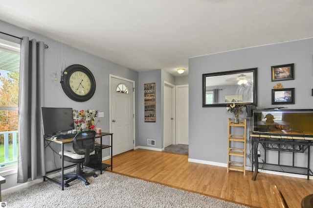 home office with baseboards, visible vents, and wood finished floors