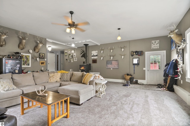 living room with a wood stove, a ceiling fan, and carpet floors