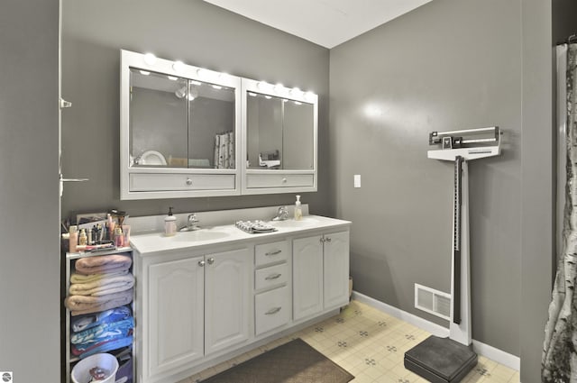 bathroom featuring baseboards, visible vents, a sink, and double vanity