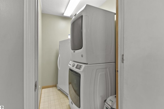 clothes washing area featuring light floors, stacked washer and dryer, and laundry area