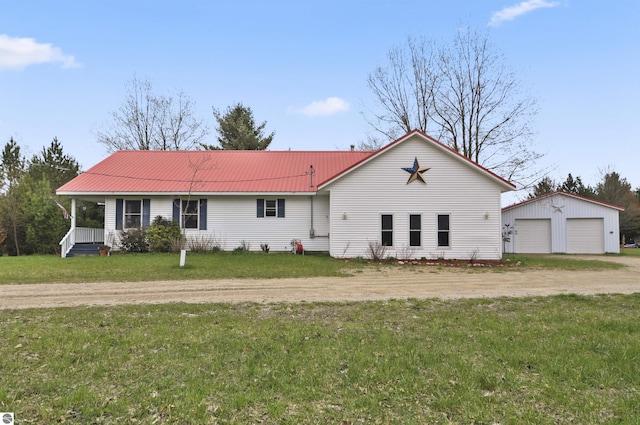 single story home featuring a front lawn, an outbuilding, metal roof, and a detached garage