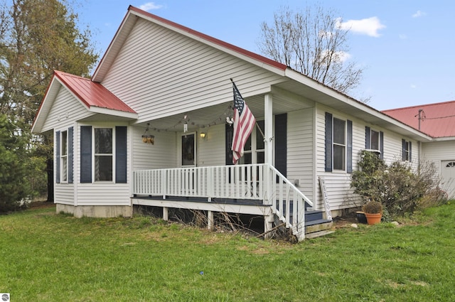 view of front facade with a front lawn, metal roof, covered porch, and an attached garage