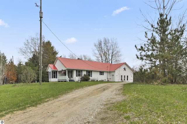 ranch-style house with dirt driveway, metal roof, and a front lawn