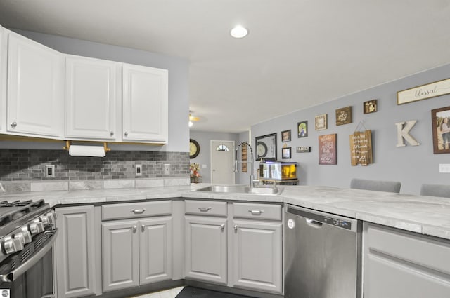 kitchen with a sink, white cabinetry, light countertops, appliances with stainless steel finishes, and tasteful backsplash