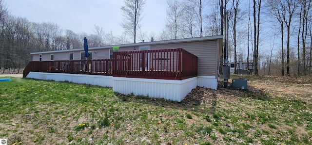 back of house featuring a lawn and a wooden deck