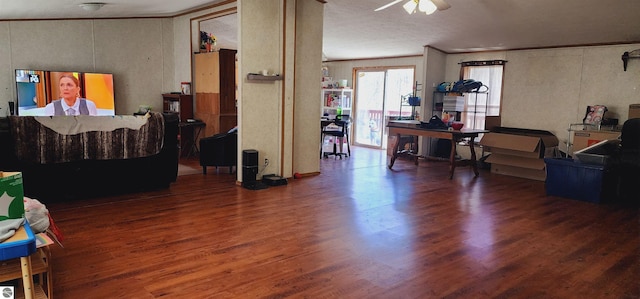 living area with crown molding, a ceiling fan, and wood finished floors