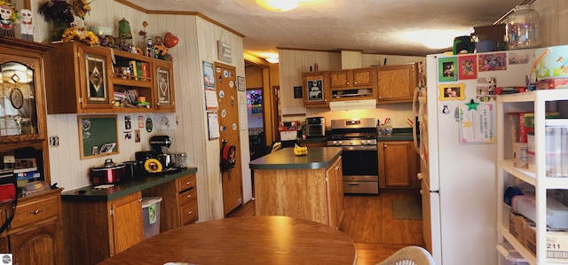 kitchen with a textured ceiling, gas range, wood finished floors, brown cabinets, and dark countertops
