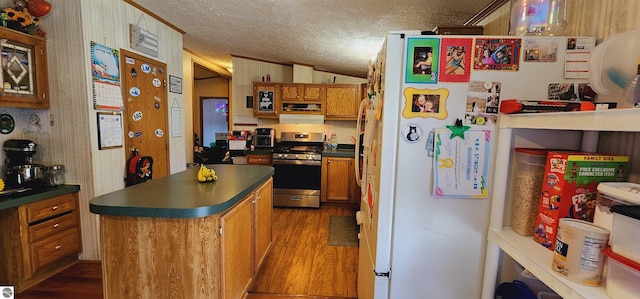 kitchen with stainless steel gas range, freestanding refrigerator, dark countertops, a textured ceiling, and dark wood-type flooring