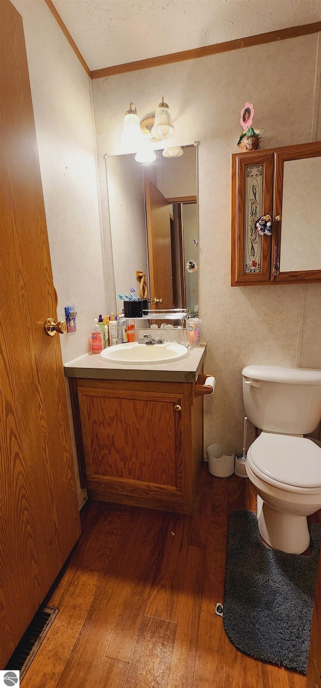 bathroom with vanity, toilet, crown molding, and hardwood / wood-style floors
