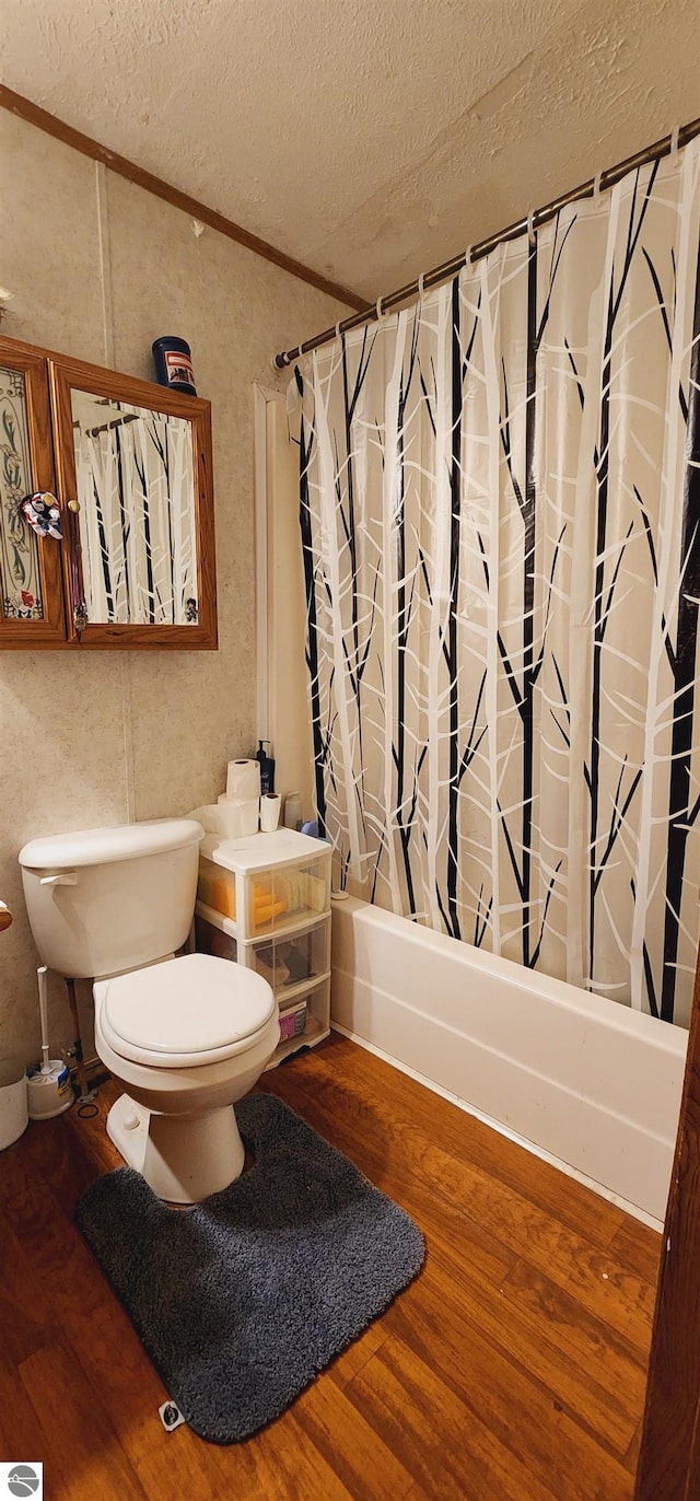 bathroom with shower / bathtub combination with curtain, a textured ceiling, toilet, and wood finished floors