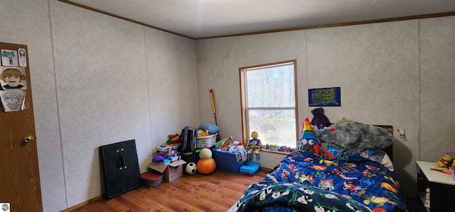 bedroom with a textured ceiling, wood finished floors, and ornamental molding