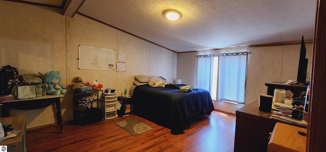 bedroom with crown molding, a textured ceiling, wood finished floors, and vaulted ceiling with beams