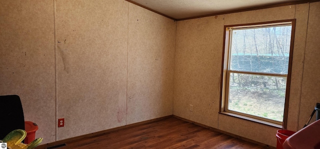spare room with a textured ceiling, visible vents, wood finished floors, and ornamental molding