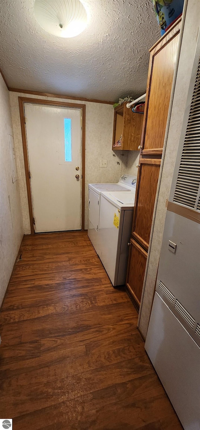 washroom featuring a heating unit, a textured ceiling, dark wood-style flooring, washing machine and clothes dryer, and cabinet space