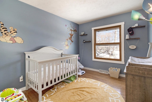 7809 Potter Rd, Bear Lake, MI 49614 - bedroom featuring baseboards, visible vents, a crib, and wood finished floors