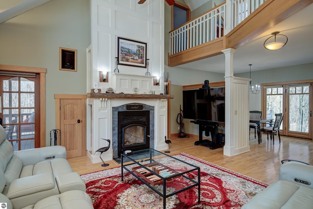 4130 W Dodge Springs Trl, Maple City, MI 49664 - living area featuring a premium fireplace, baseboards, ceiling fan with notable chandelier, a towering ceiling, and wood finished floors