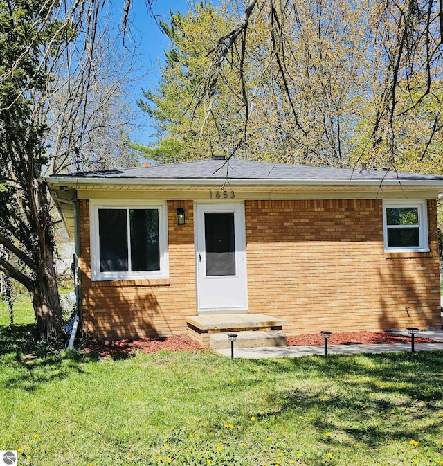 view of front facade with brick siding and a front yard