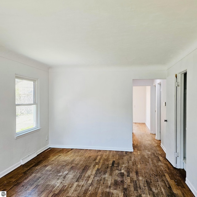 spare room with baseboards, visible vents, and wood finished floors